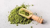 green moringa leaf powder and a wooden scooping spoon