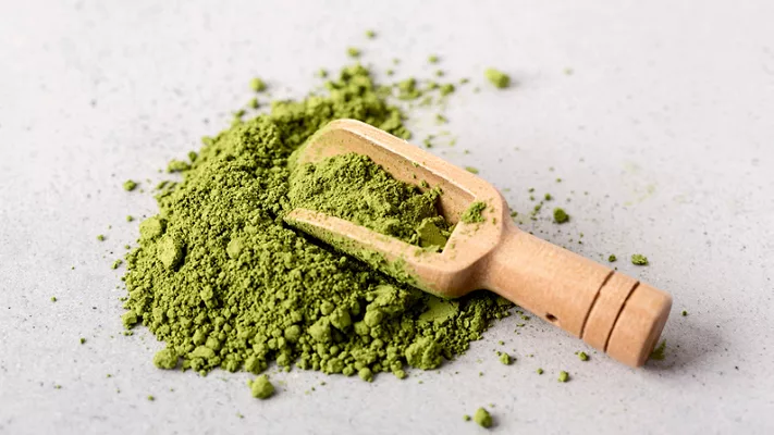 green moringa leaf powder and a wooden scooping spoon