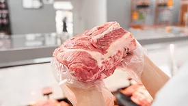 grocer's hands holding a hunk of beef