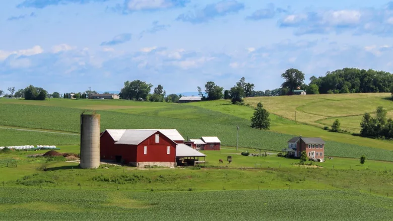 red barn, silo, and farmhouse on farmland in iowa