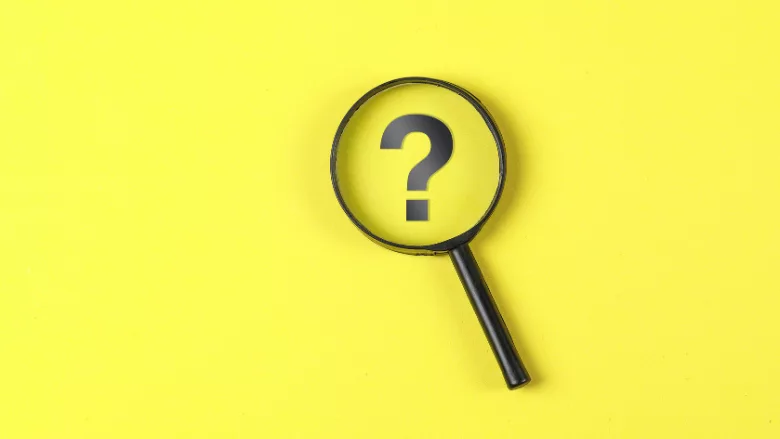 magnifying glass hovering over question mark on yellow background