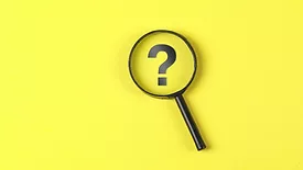 magnifying glass hovering over question mark on yellow background