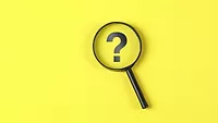 magnifying glass hovering over question mark on yellow background
