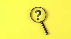 magnifying glass hovering over question mark on yellow background