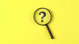 magnifying glass hovering over question mark on yellow background