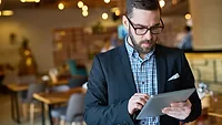 official looking man in suit checking tablet in foodservice establishment
