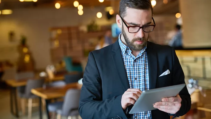 official looking man in suit checking tablet in foodservice establishment