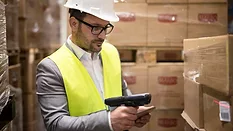 man scanning lot code on box in warehouse_aleksanderlittlewolf via Magnific.png man in a suit with hard hat and reflective vest scanning barcode on box in warehouse
