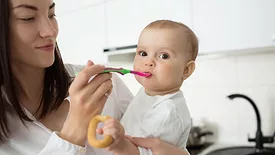 a mother holding and spoon feeding her baby