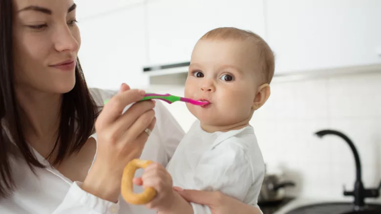 a mother holding and spoon feeding her baby