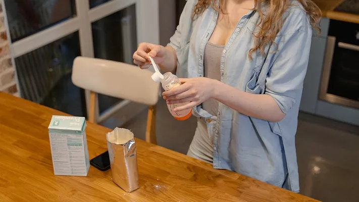 mother preparing bottle of infant formula_MART PRODUCTION via Pexels.png mother preparing bottle of infant formula