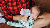 newborn baby in mom's lap taking a bottle