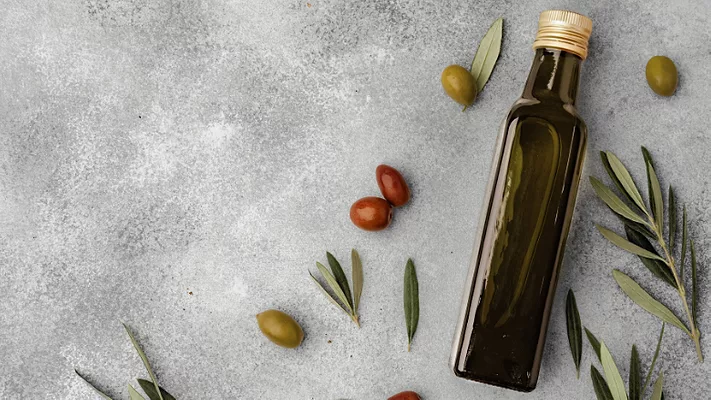 olive oil bottle and olives on gray background