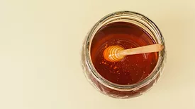 overhead view of a jar of honey with wand in it