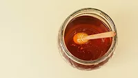 overhead view of a jar of honey with wand in it