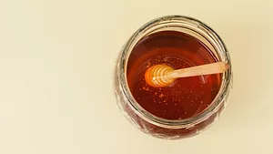 overhead view of a jar of honey with wand in it