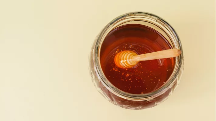 overhead view of a jar of honey with wand in it