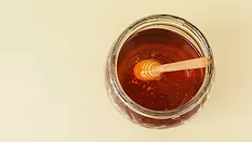 overhead view of a jar of honey with wand in it