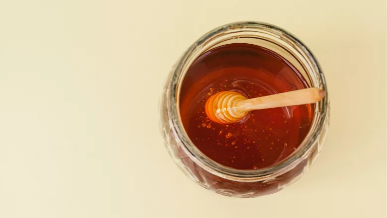 overhead view of a jar of honey with wand in it