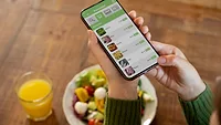 person eating a meal and holding a smartphone displaying online food ordering service