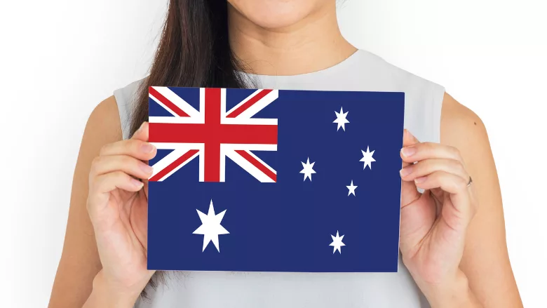person holding up card with a depiction of the Australian flag