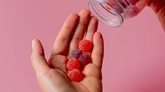 person pouring supplement gummies into hand