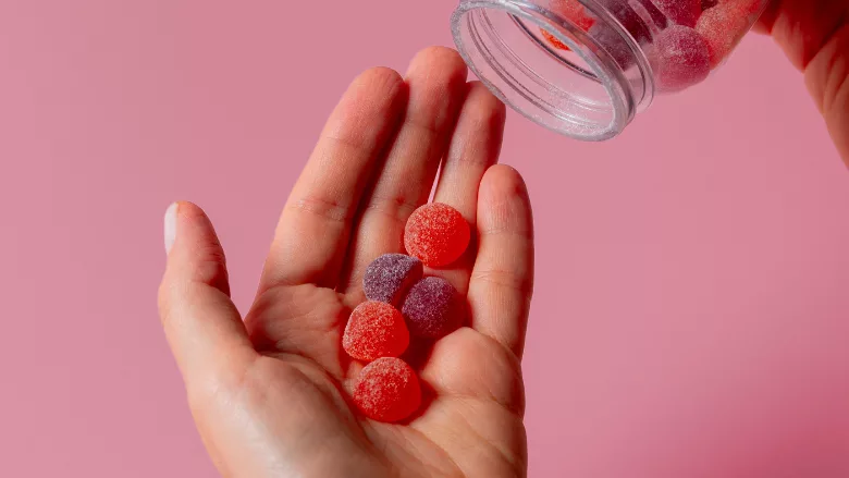 person pouring supplement gummies into hand