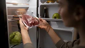 person taking vacuum packed meat out of fridge