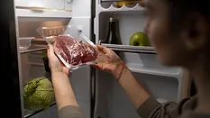 person taking vacuum packed meat out of fridge
