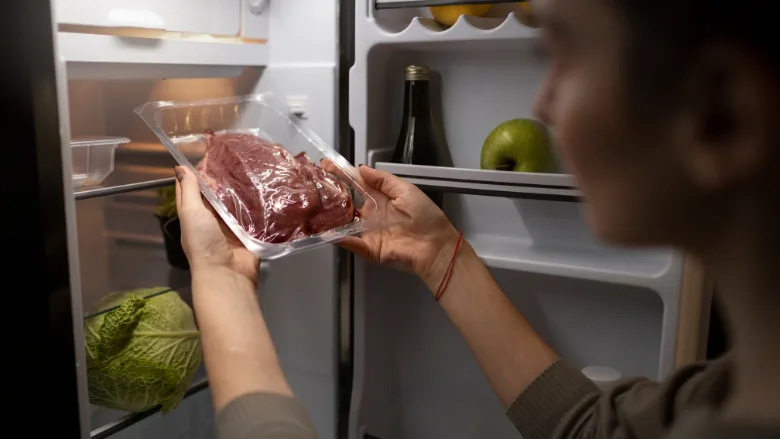 person taking vacuum packed meat out of fridge