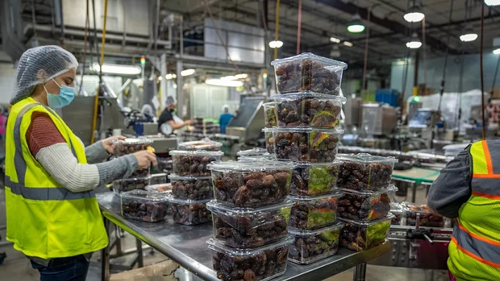 person working in date production factory wearing a covid-19 era mask