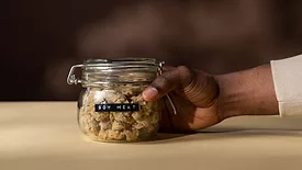 a person's hand holding a jar labeled "soy meat" filled with soy meat product