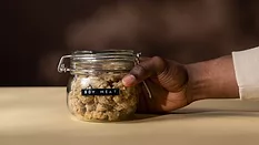 a person's hand holding a jar labeled "soy meat" filled with soy meat product