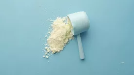 scoop of white powder supplement on blue background