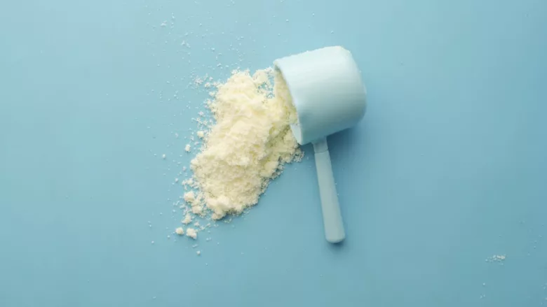 scoop of white powder supplement on blue background