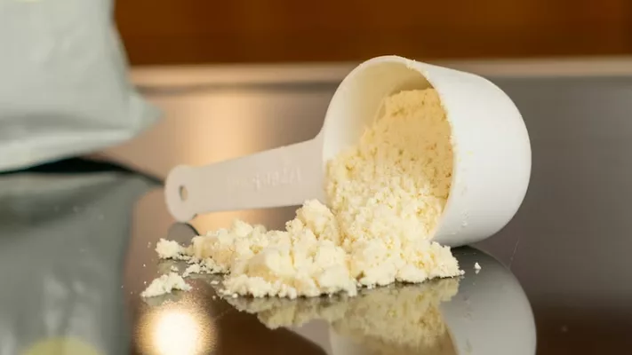 scoop of yellowish white formula milk powder