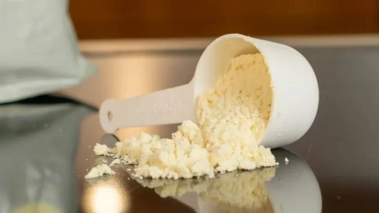 scoop of yellowish white formula milk powder