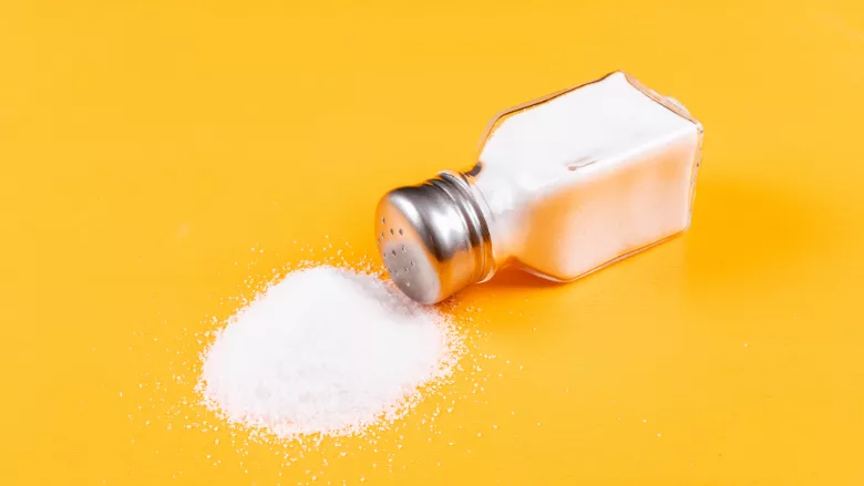 spilled salt shaker against a yellow background
