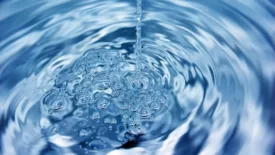 a stream of water falling into a swirling pool of clear blue