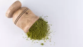 green powder/moringa in wooden mortar