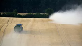 trucks spraying pesticides across wheat field