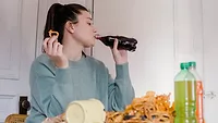 Woman eating chips and drinking soda