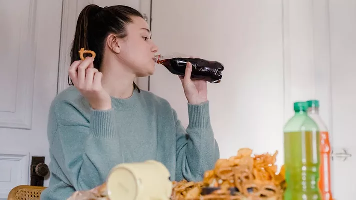 Woman eating chips and drinking soda