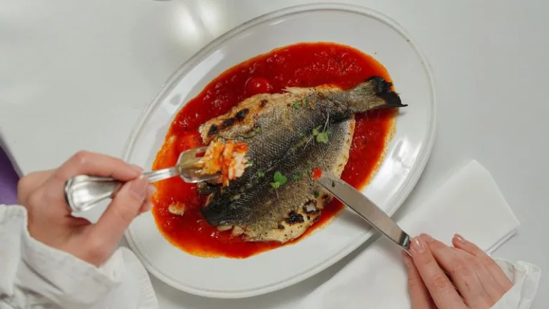 cutting into a plate of fish