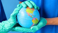 gloved doctors' hands holding a globe showing the americas