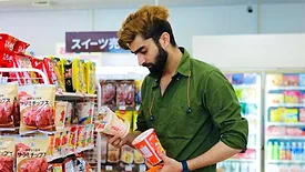 man in market reading food labels