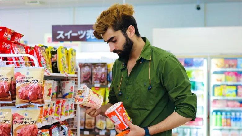 man in market reading food labels