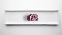 slice of dark red glistening meat on sterile white background