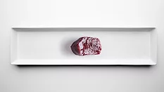 slice of dark red glistening meat on sterile white background