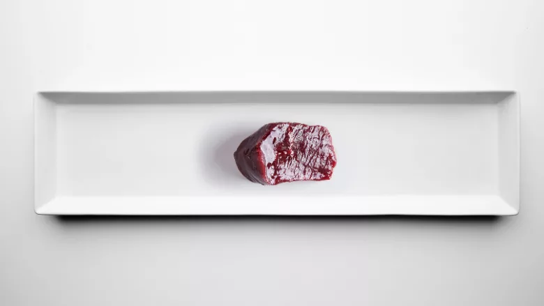 slice of dark red glistening meat on sterile white background